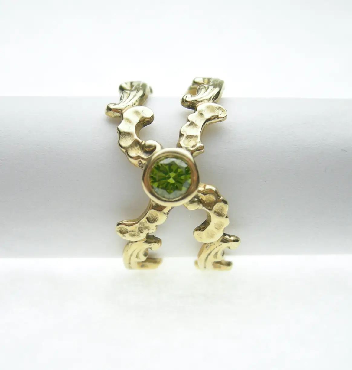 The Living Current Ring — hand-carved 14kt gold double scroll with a bezel-set green diamond